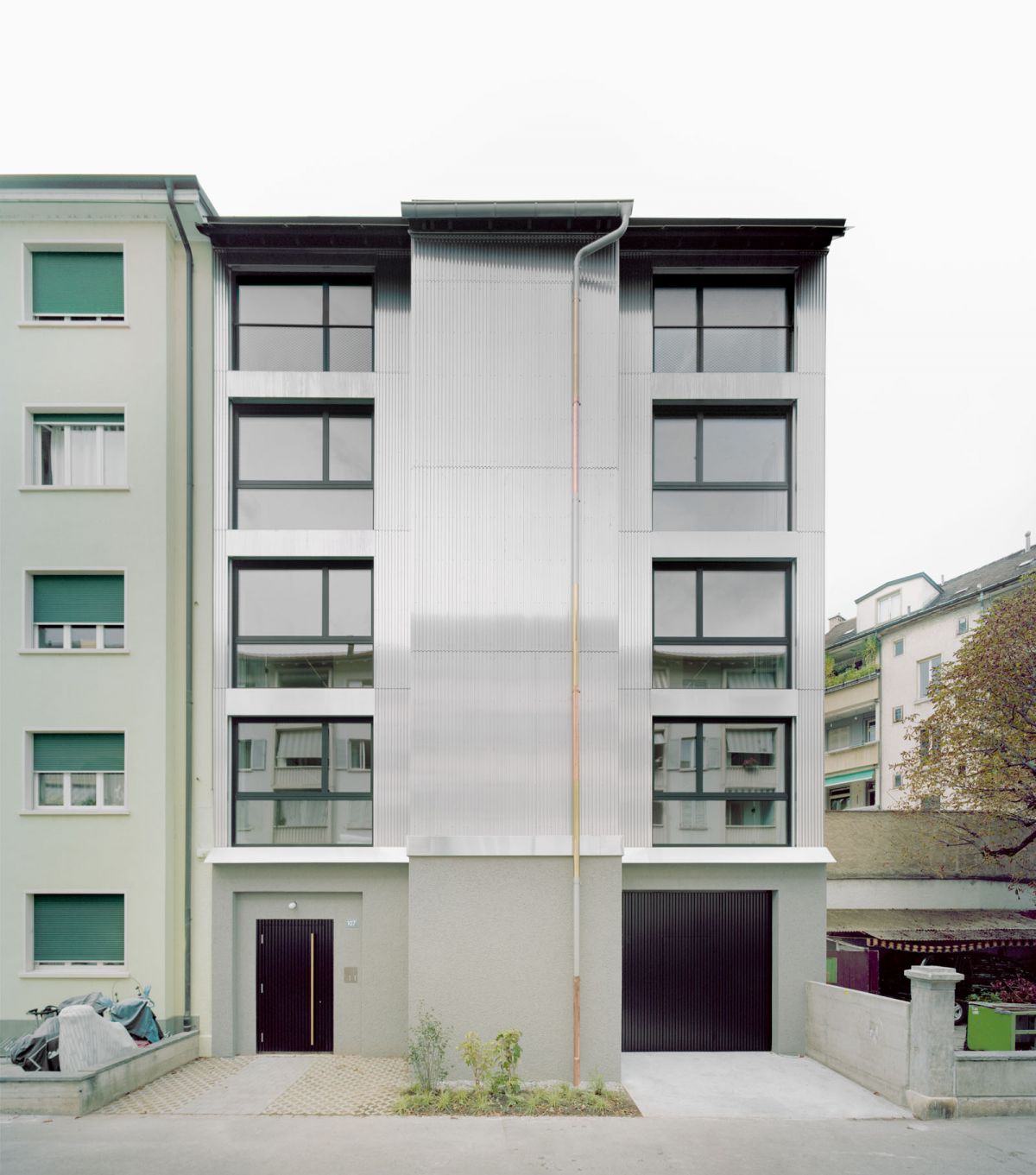 Die Aufstockung führt strassenseitig die Traufhöhe der Nachbarliegenschaft weiter und interpretiert den benachbarten Dachabschluss als Sheddach neu 01_Erfinger107_Ostfassade_Offen_Lukas_Raeber_Architekten_%C2%A9Rasmus_Norlander